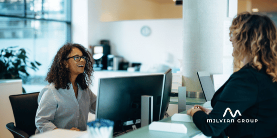 two workers talking at a desk